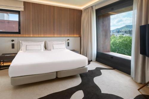 a bedroom with a white bed and a large window at Hotel Meliá Bilbao in Bilbao