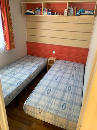 2 lits se trouvent dans une chambre avec un mur dans l'établissement Mobilhome a 5 min de la mer à pied camping 5etoiles, à Saint-Georges-de-Didonne
