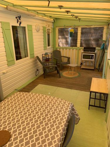 - une véranda avec un lit et une table dans l'établissement Mobilhome a 5 min de la mer à pied camping 5etoiles, à Saint-Georges-de-Didonne