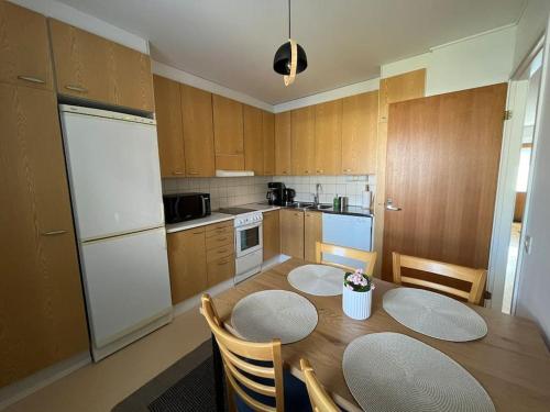 a kitchen with a table and chairs and a white refrigerator at Vääksy rivitalo 62 m2 in Asikkala