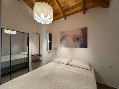 a bedroom with a white bed and a chandelier at Xasteria apartment Ξαστεριά in Poros