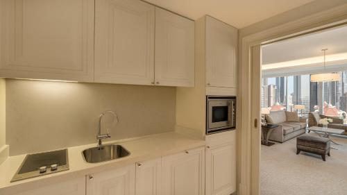 a kitchen with white cabinets and a view of a living room at Kempinski The Boulevard Dubai in Dubai