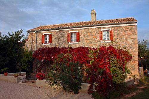 a stone house with red flowers in front of it at Mala kuća za veliki odmor in Šilo
