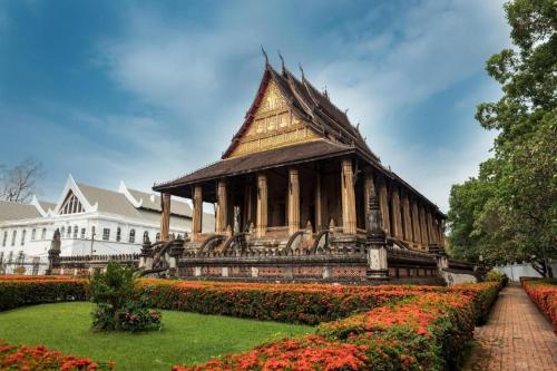 a pagoda in a garden in front of a building at Senesouk Hotel in Vientiane