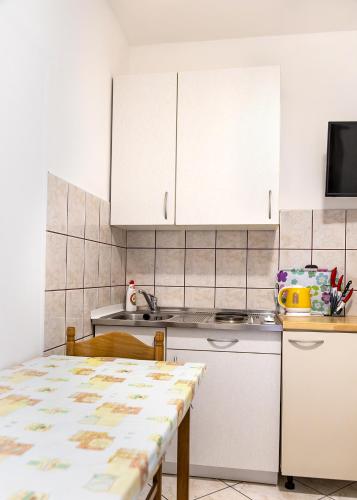 a kitchen with white cabinets and a table at Apartment Anamaria in Pag