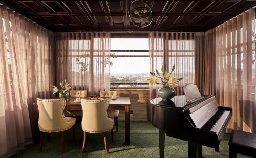a dining room with a piano and a table with chairs at NIA Hotel in Da Lat