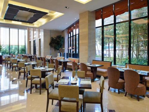 a restaurant with tables and chairs and windows at Putian Depo Hotel in Putian