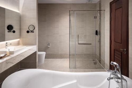 a bathroom with a bath tub and a shower at RIVA Hotel SHV in Sihanoukville