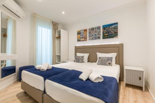 a bedroom with two beds with blue sheets at BRA.com Apartments Oporto Campanhã in Porto