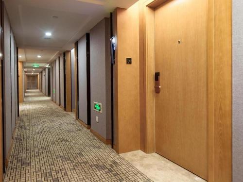 an empty hallway with wooden doors and a tile floor at Kyriad Marvelous Hotel·Xi'an North High-speed Railway Station in Xi'an