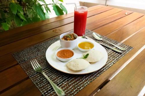 a plate of food on a table with a drink at OYO 299 Randula Grand Venus Hotel in Katuwalamulla