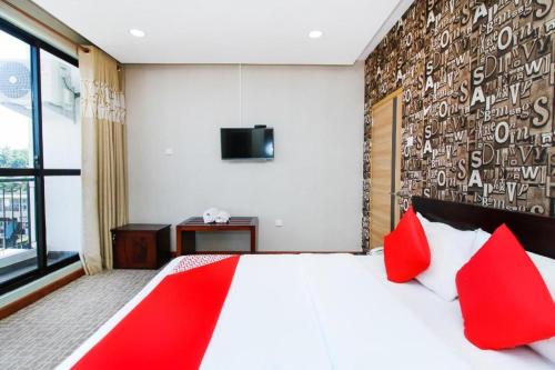 a bedroom with a large bed with red pillows at OYO 299 Randula Grand Venus Hotel in Katuwalamulla