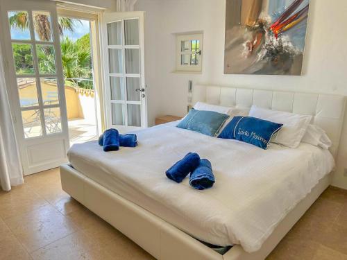 Elle comprend un grand lit blanc avec des oreillers bleus. dans l'établissement La California, à Sainte-Maxime
