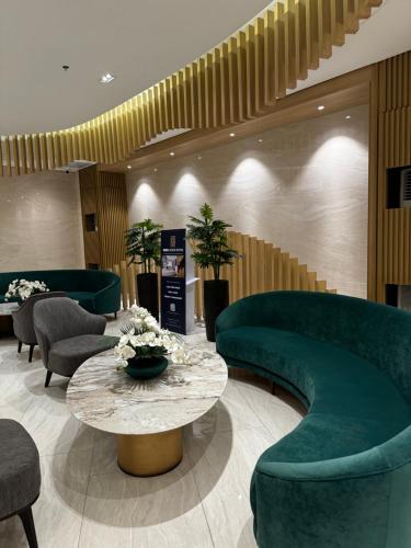 a lobby with green chairs and a table and chairs at Makati apartment - Lush Residences in Manila