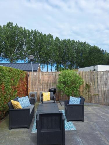 a patio with three chairs and a table with pillows at Stelle Maris, Nice place in Heinkenszand, 2 bedrooms, outdoor swimming pool, WIFI smart TV and privacy in Heinkensand