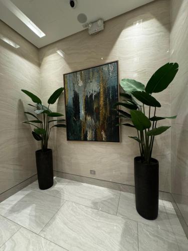 two plants in black vases on a wall with a painting at Makati apartment - Lush Residences in Manila