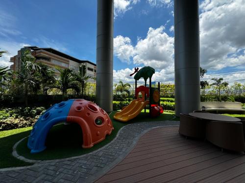 a playground with a slide and a child on a slideintend at Makati apartment - Lush Residences in Manila