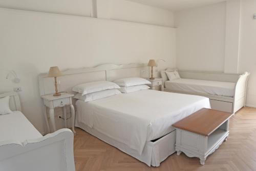 a white bedroom with two beds and a table at Adagio Salentino in Porto Cesareo