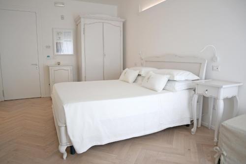 a white bedroom with a white bed and a table at Adagio Salentino in Porto Cesareo