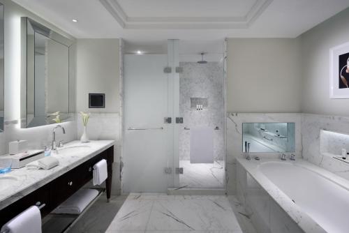 a white bathroom with a tub and a shower at Kempinski The Boulevard Dubai in Dubai