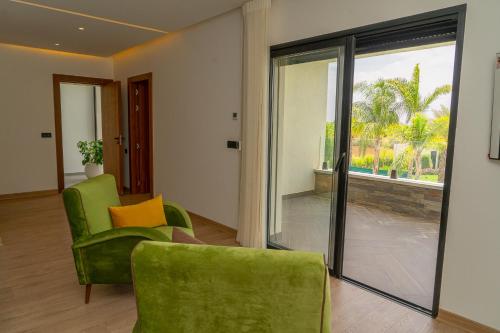 a living room with green chairs and a sliding glass door at Villa Marrakech vue atlas in Marrakech