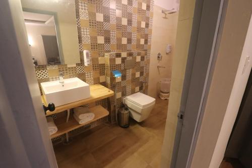 a bathroom with a sink and a toilet and a mirror at Aamod Feather Touch - Nainital in Nainital