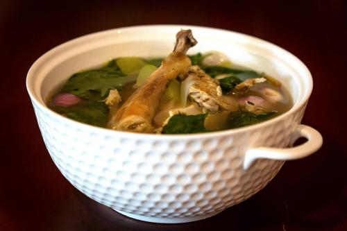 a white bowl of soup with chicken in it at DCCCO Hotel in Dumaguete