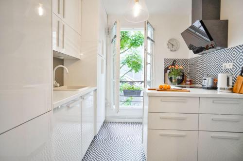 une cuisine avec des armoires blanches et une fenêtre dans l'établissement Trocadéro - Genuine Apartment, à Paris