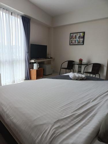 a bedroom with a large white bed and a television at Tisa Hotel Udonthani in Udon Thani