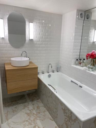 a bathroom with a tub and a sink and a mirror at Appartement privé avec jardin in Boulogne-Billancourt