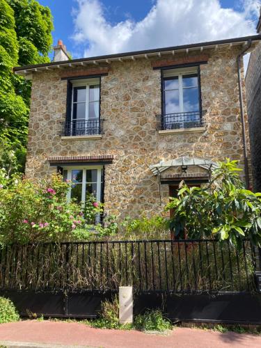 an old stone house with windows and a fence at Appartement privé avec jardin in Boulogne-Billancourt