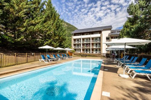 a swimming pool with chairs and umbrellas and a hotel at Résidence Pierre & Vacances Les Trois Domaines in Ax-les-Thermes