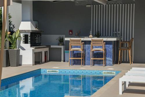 a kitchen and a swimming pool with two chairs and a table at Dareia Suites in Plános