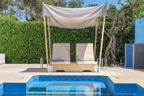 a gazebo with two chairs next to a pool at Dareia Suites in Plános