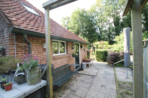 a brick house with a porch and a patio at Karin's kruidenhoeve appartement Goudsbloem in Lutten