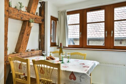 une salle à manger avec une table, des chaises et des fenêtres dans l'établissement La Légende des 2 Pierres, à Eguisheim