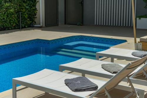 a swimming pool with two lounge chairs and a swimming pool at Dareia Suites in Plános