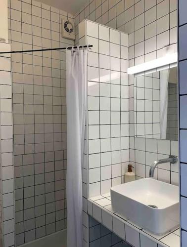 La salle de bains est pourvue de carrelage blanc, d'un lavabo et d'un miroir. dans l'établissement Superbe appartement 2 personnes, à Paris
