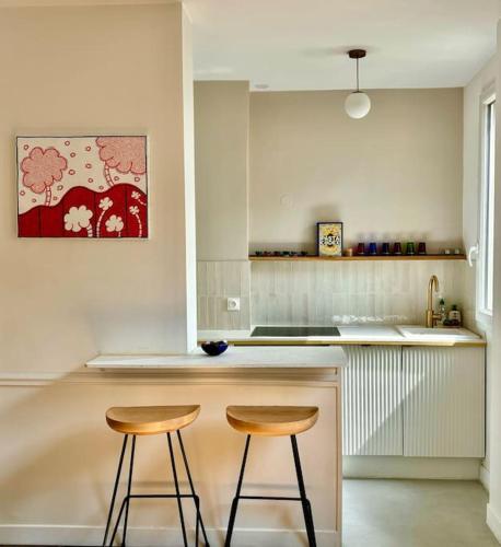 une cuisine avec deux tabourets sur un comptoir de cuisine dans l'établissement Superbe appartement 2 personnes, à Paris