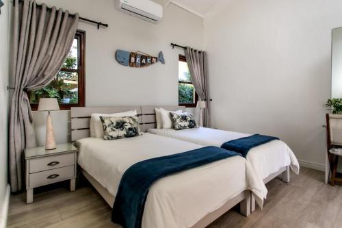 two beds in a bedroom with white walls at Sixteen Guesthouse on Main in Hermanus
