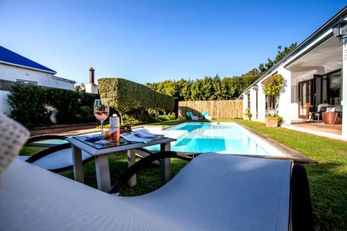 a table with a glass of wine next to a pool at Sixteen Guesthouse on Main in Hermanus