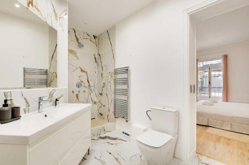 une salle de bain blanche avec des toilettes et un lavabo dans l'établissement Chic flat with garden terrace -4BR-12P - Trocadéro, à Paris