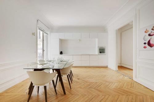 - une cuisine blanche avec une table à manger et des chaises dans l'établissement Chic flat with garden terrace -4BR-12P - Trocadéro, à Paris