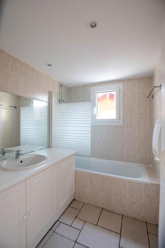 une salle de bain avec une baignoire, un lavabo et un miroir dans l'établissement Appartement 29 Plages à pied, à Capbreton