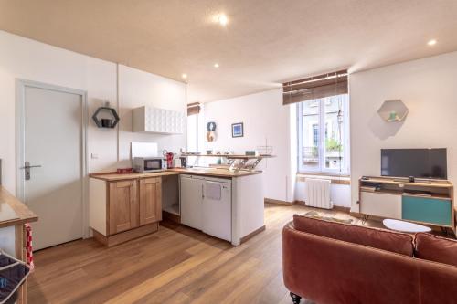 Il dispose d'une cuisine ouverte et d'un salon avec un canapé. dans l'établissement Hypercentre - Proche Parking Gratuit - Fibre - Calme, à Narbonne