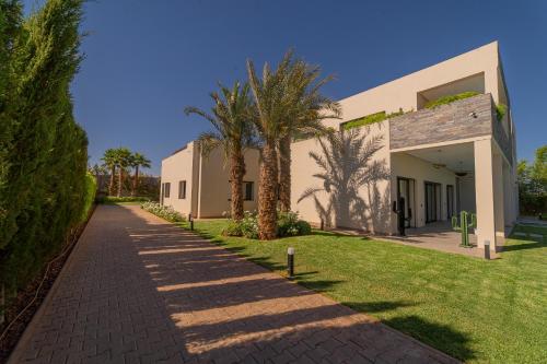 a brick sidewalk next to a building with palm trees at Villa Marrakech vue atlas in Marrakech