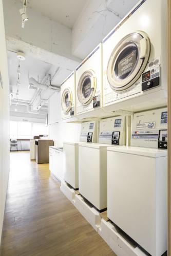 a room with three washing machines on the wall at Hostel OGK in Osaka