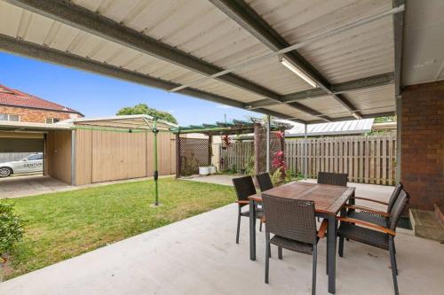 a patio with a wooden table and chairs at Klingner House in Redcliffe