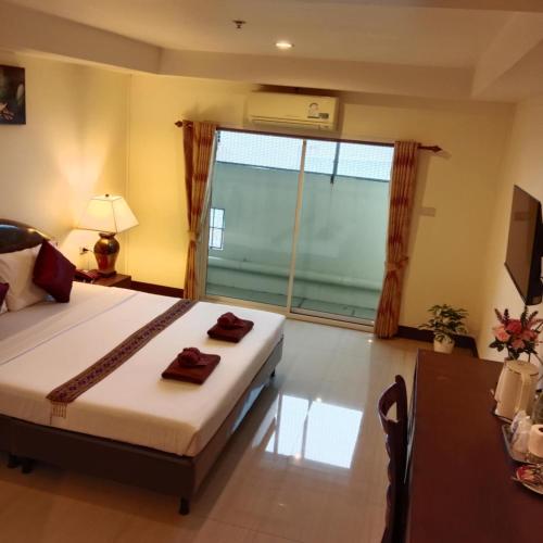 a bedroom with a bed and a large window at Pearl Place Hotel in Hat Yai
