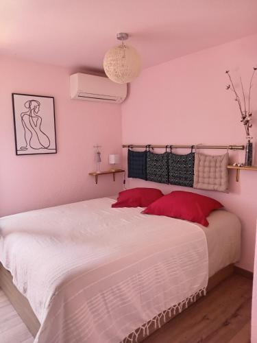 une chambre avec un grand lit blanc avec des oreillers rouges dans l'établissement La Bulle temporelle d'Hélène, à Saint-Cyprien